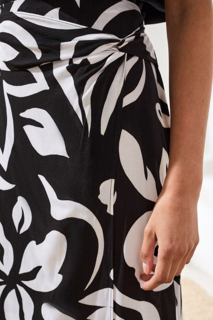 Close-up of black and white textured midi skirt with bold floral print and wrap-front detail by Tribal, showing hand at side.