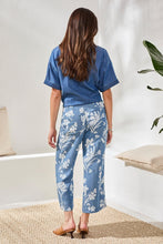 Rear view of woman wearing Tribal Denim Printed Wide Leg Crop Pant with white floral pattern styled with denim top