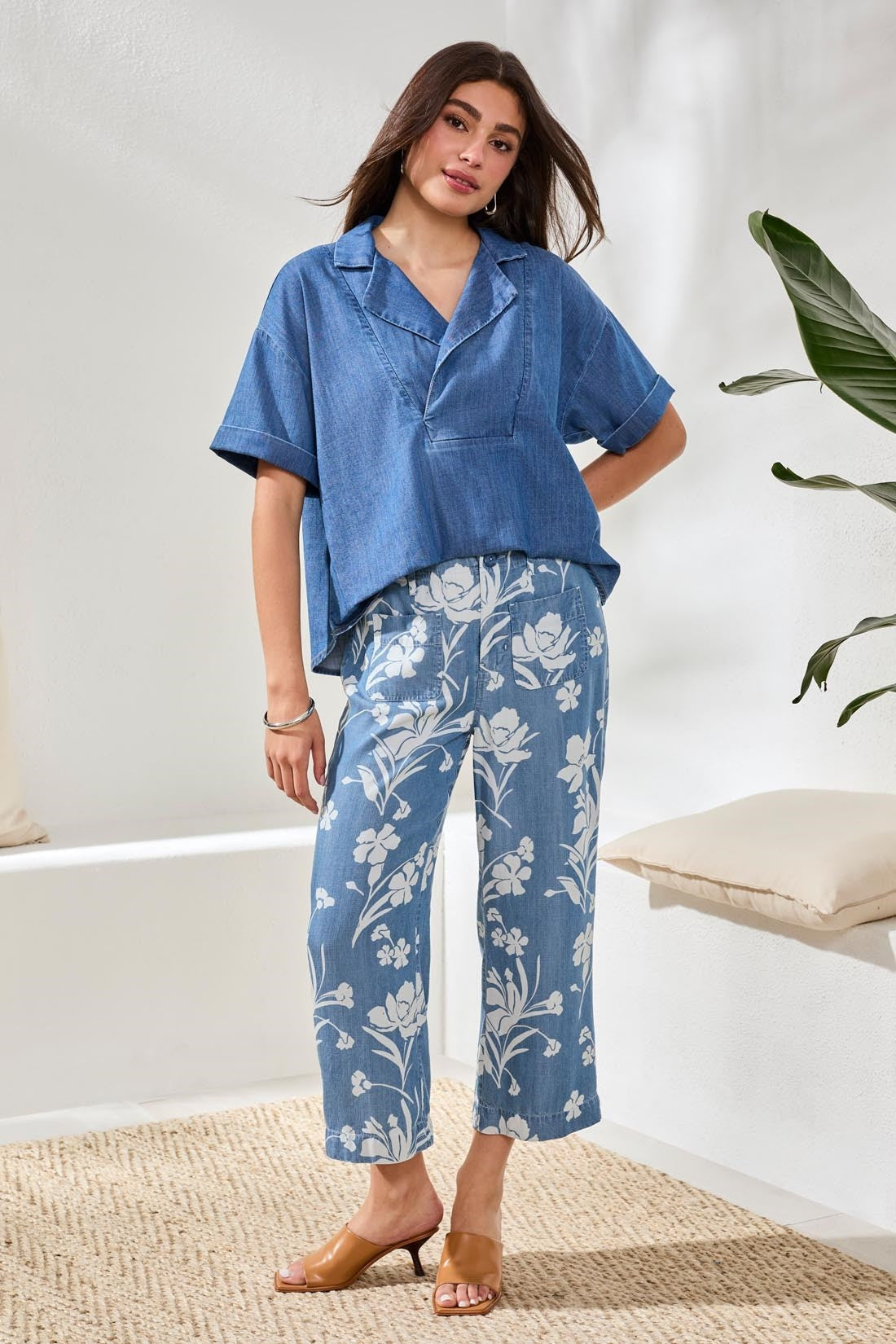 Woman wearing Tribal Denim Printed Wide Leg Crop Pant in blue with white floral print styled with loose denim shirt and brown heels