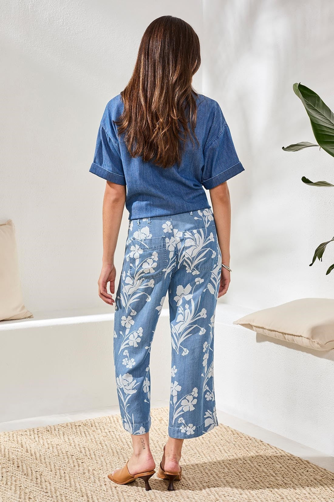 Rear view of woman wearing Tribal Denim Printed Wide Leg Crop Pant with white floral pattern styled with denim top