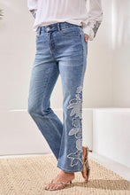 Woman wearing Tribal Embroidered Sophia Curvy Flare jeans in light blue denim with floral embroidery on leg by Tribal