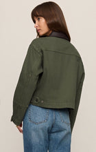Woman wearing a green Dusk Sage Rey Cropped Chore Jacket by z supply, shown from the back with denim jeans