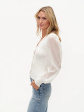 Woman wearing White Celeste Mixed Media Top by six/fifty paired with light blue jeans, posing sideways on white background