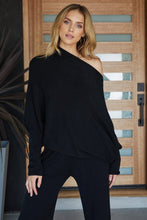 Milio Milano black asymmetrical off-shoulder sweater styled with black pants