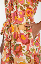 Close-up of a hand in the pocket of the Tan Floral Short Sleeve Shirred Button Front Woven Dress by liverpool showing vibrant floral print and waist tie.
