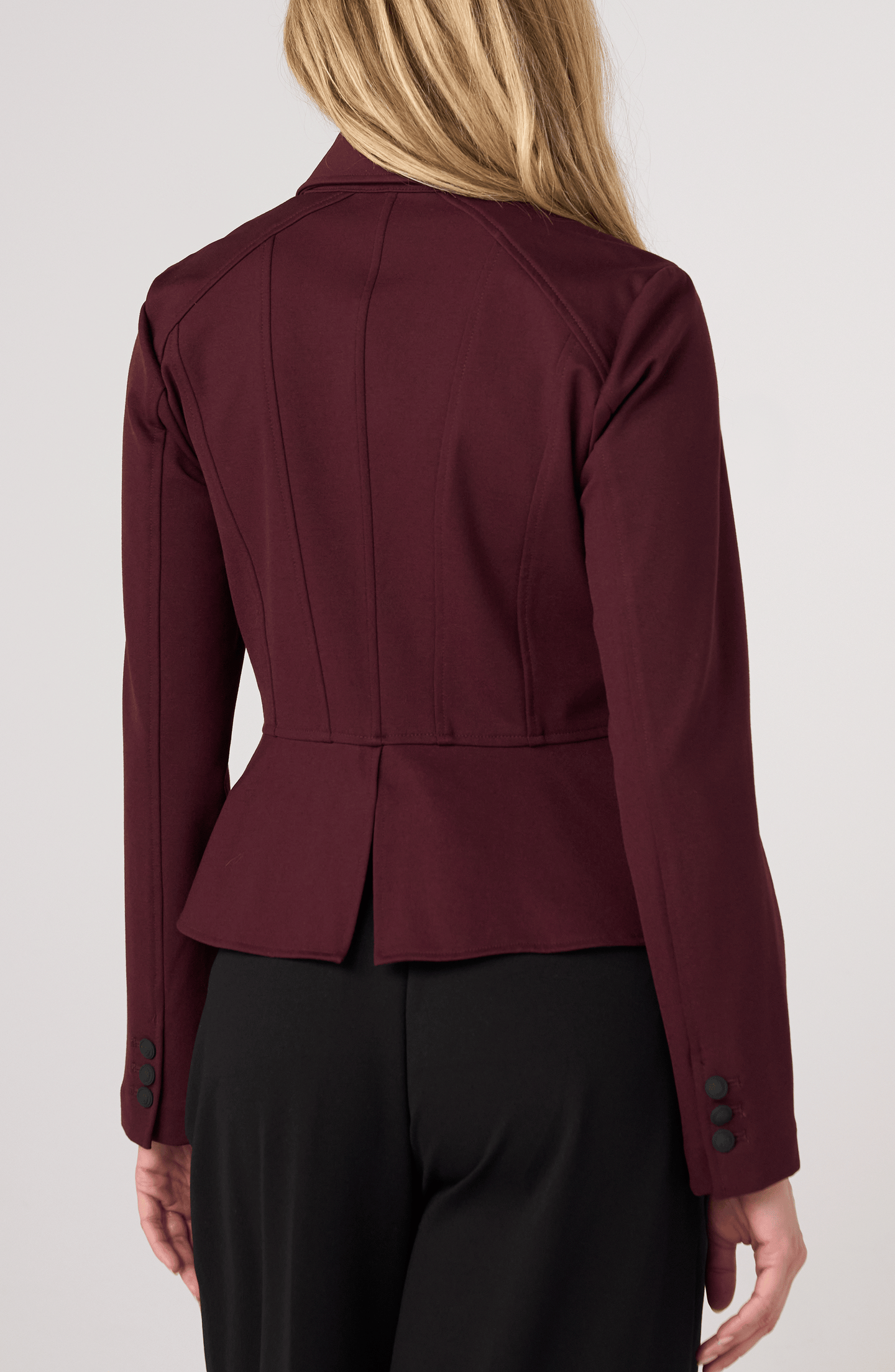Back view of a woman wearing a tailored Dark Oxblood Peplum Jack by liverpool with long sleeves and button details.