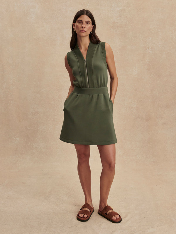 Woman wearing olive green sleeveless Thyme Polyanna Half Zip Dress by Varley with zip front and side pockets
