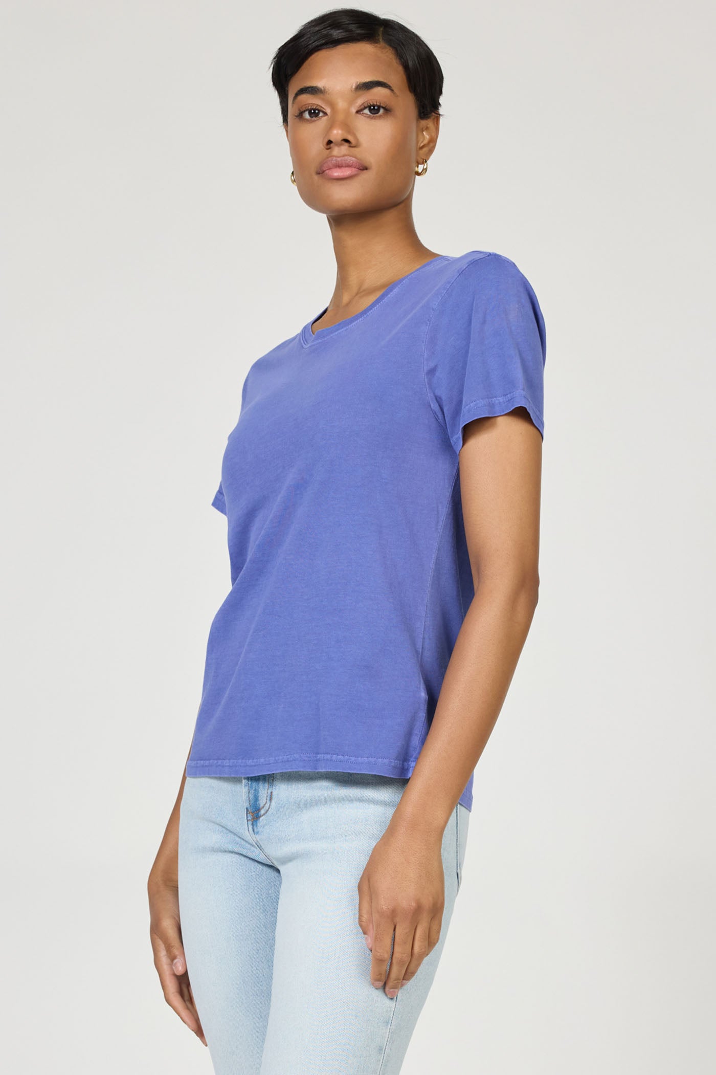 Woman wearing Pigment Skipper Blue Unity Tee by dear john paired with light blue jeans against a plain background