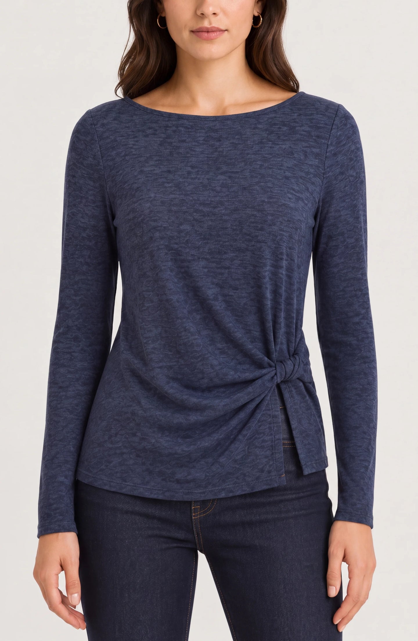 Woman wearing a navy long sleeve top with a side knot and dark jeans
