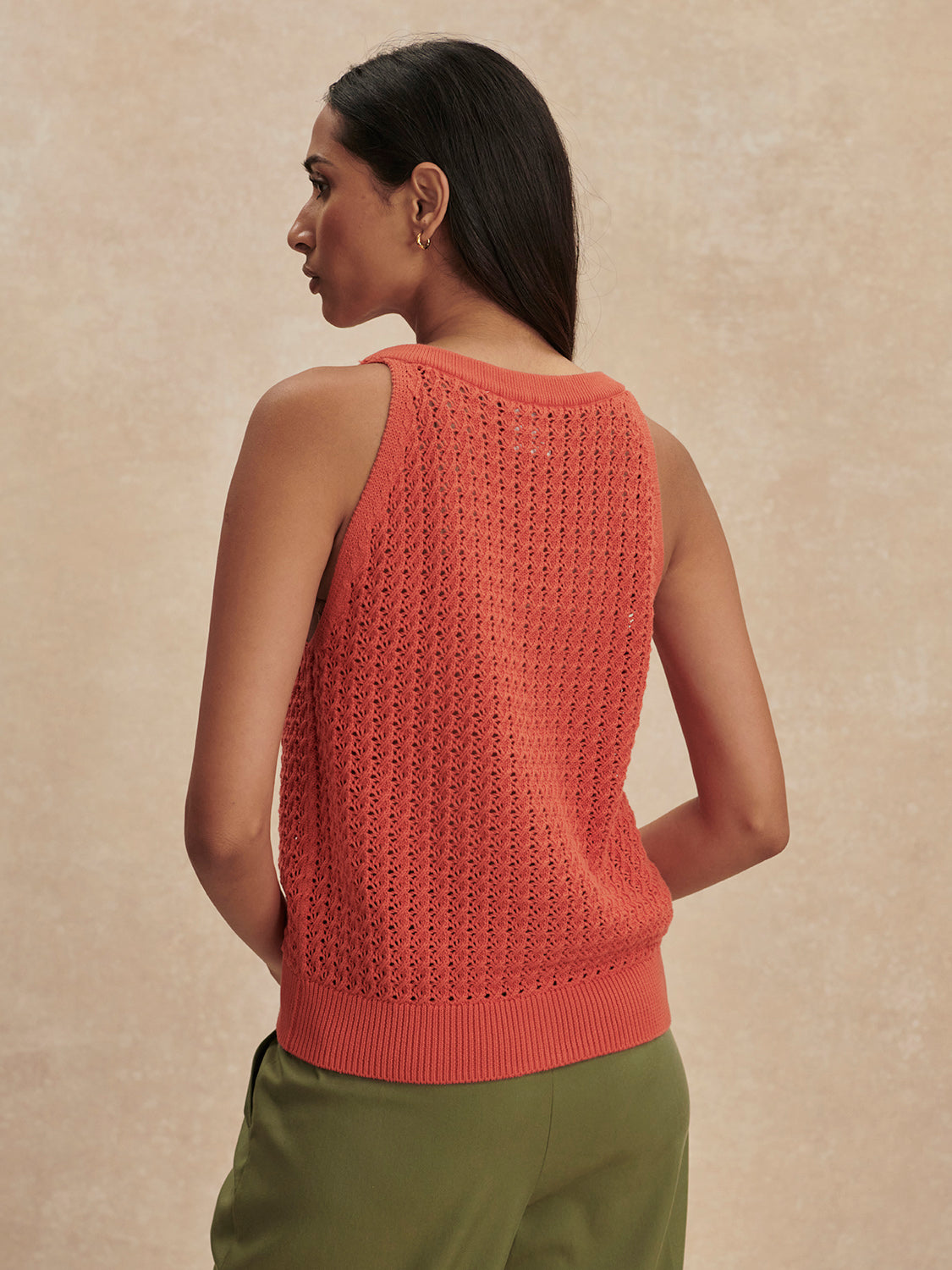 Woman seen from behind wearing a coral Summer Fig Alessia Knit Tank by Varley with green pants against beige background