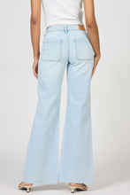 Rear view of a model wearing light wash Misty Cloud Micah Jeans by dear john with a flared leg and raw hem details