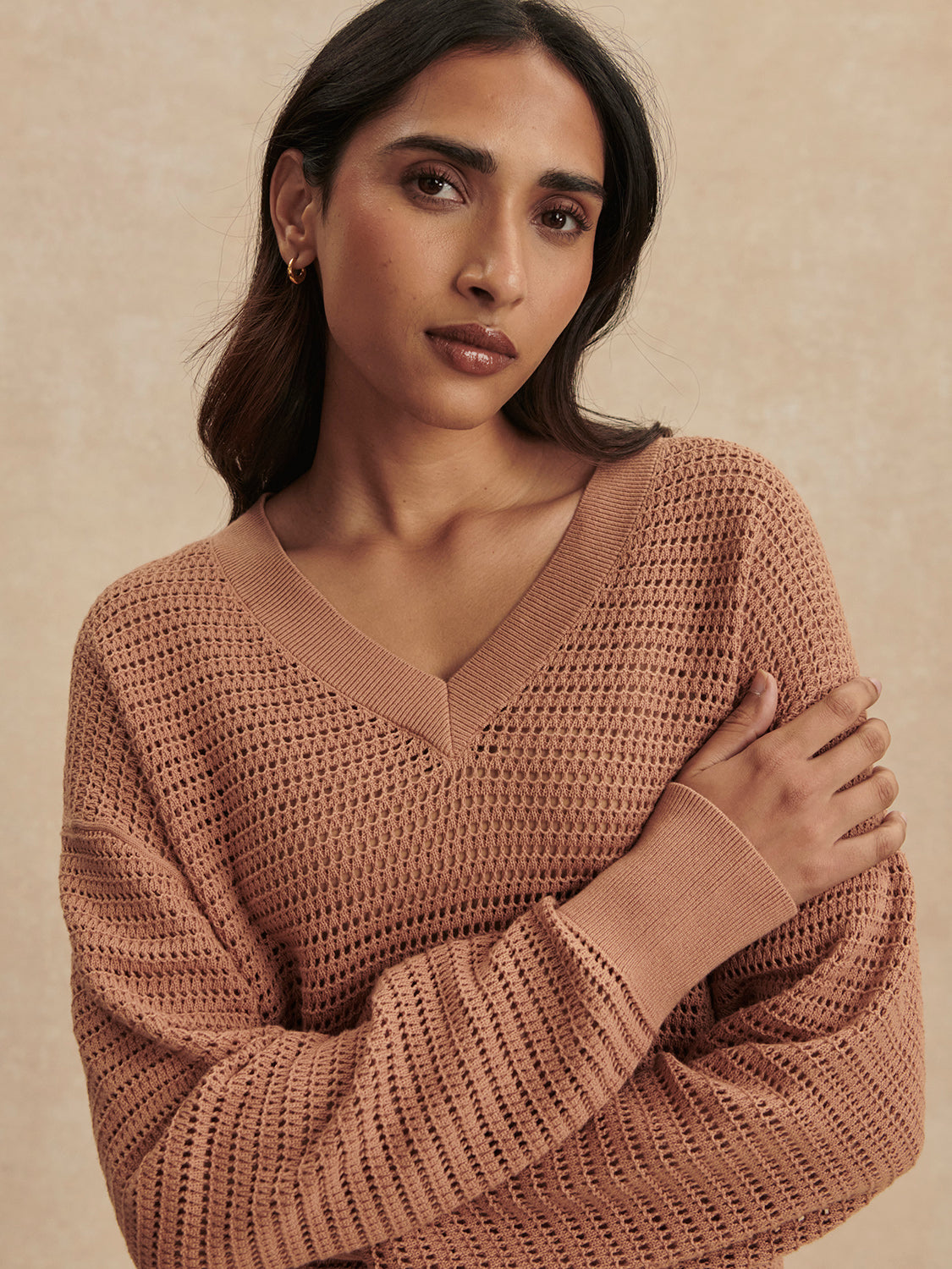 Woman wearing a camel Camel Gaia V Neck Sweater by Varley with textured knit and ribbed cuffs against neutral background