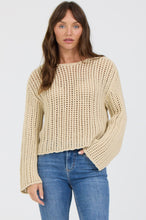 Woman wearing beige Mojave Desert Adela Sweater by dear john paired with blue jeans against white background