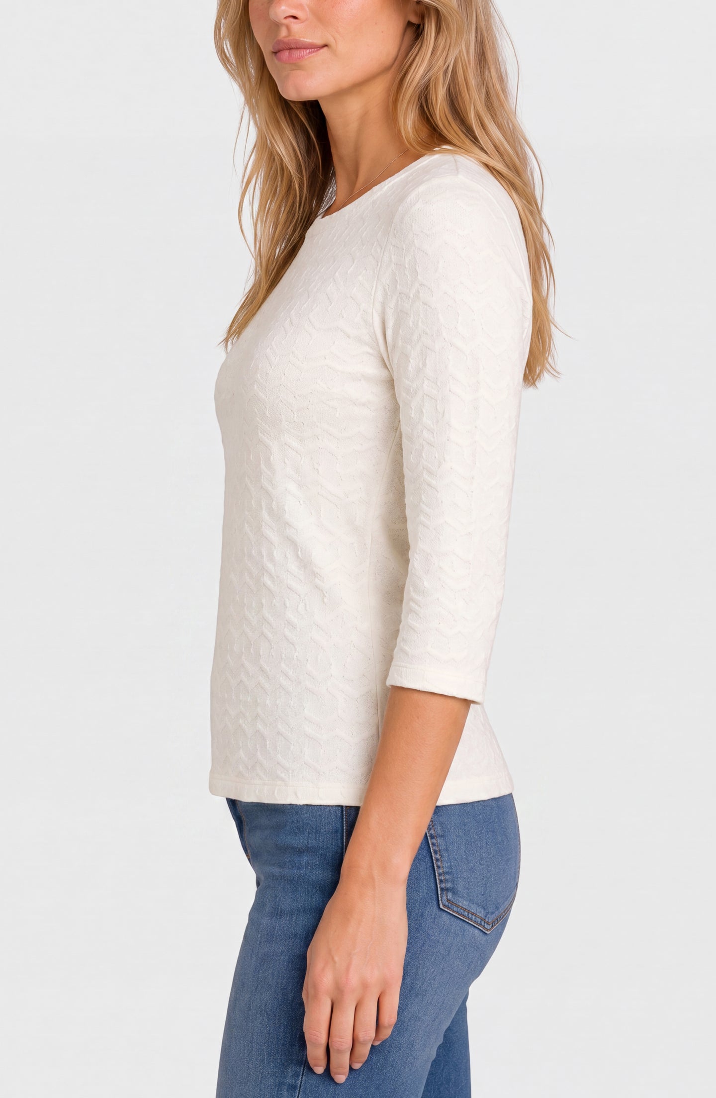 Woman wearing a cream textured three-quarter sleeve top and blue jeans, shown from the side against a plain background.