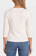 Woman wearing a white textured long sleeve top and blue denim jeans shown from the back on a plain background.
