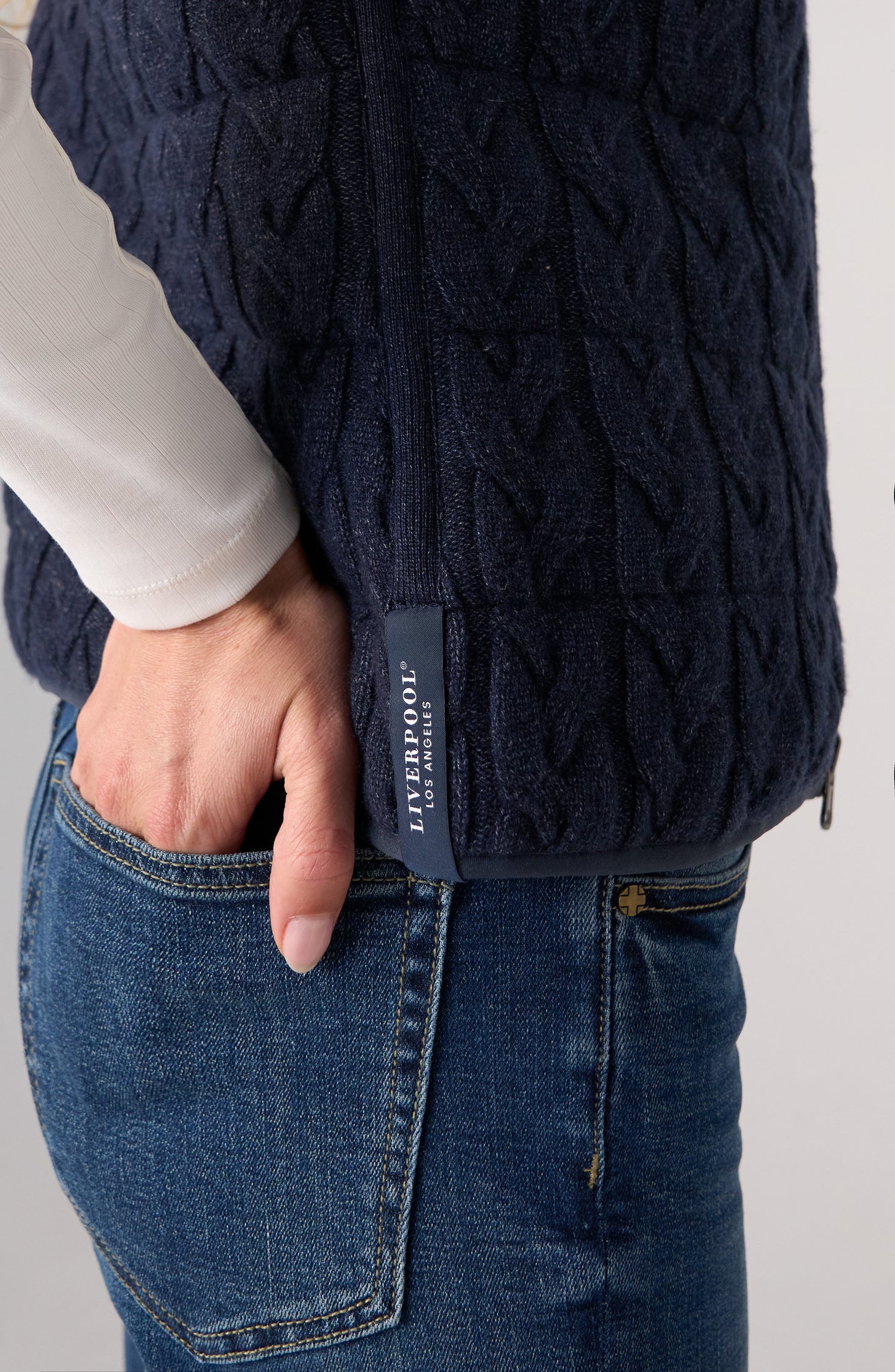 Close-up of hand in pocket wearing Heather Navy Reversible Zip Front Quilted Sweater Vest by liverpool over jeans