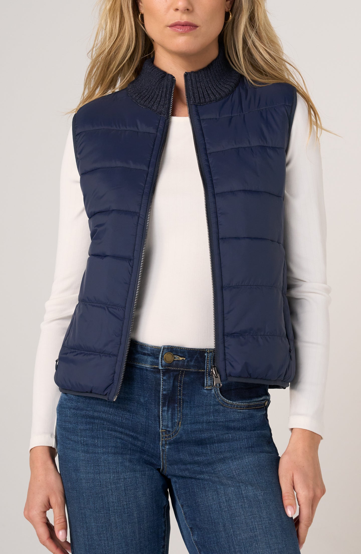 Woman wearing a Heather Navy Reversible Zip Front Quilted Sweater Vest by liverpool over white top and blue jeans