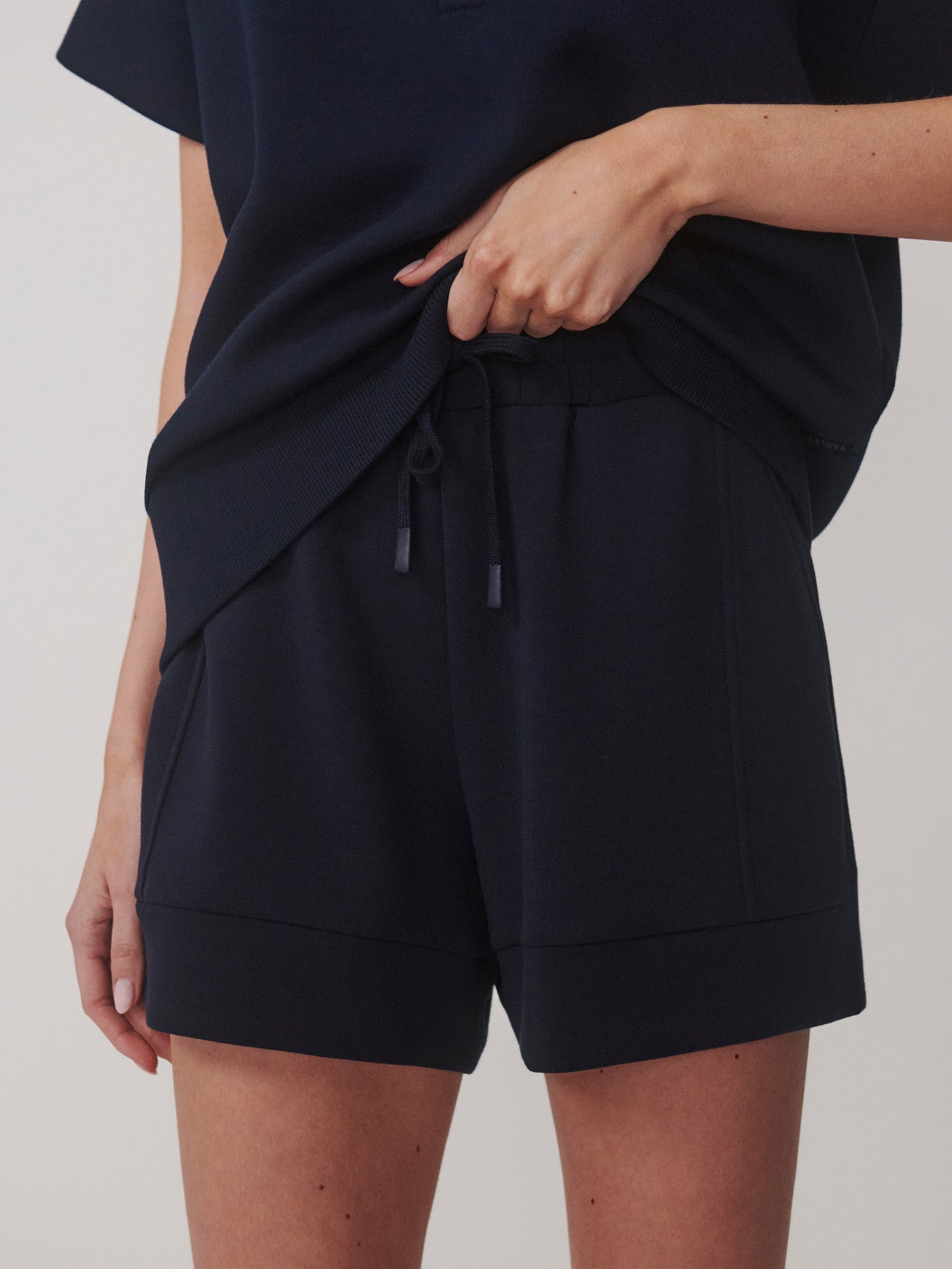 Woman wearing Navy Atrium High Rise Short 4.5 by Varley with a matching navy top, featuring a drawstring waist.