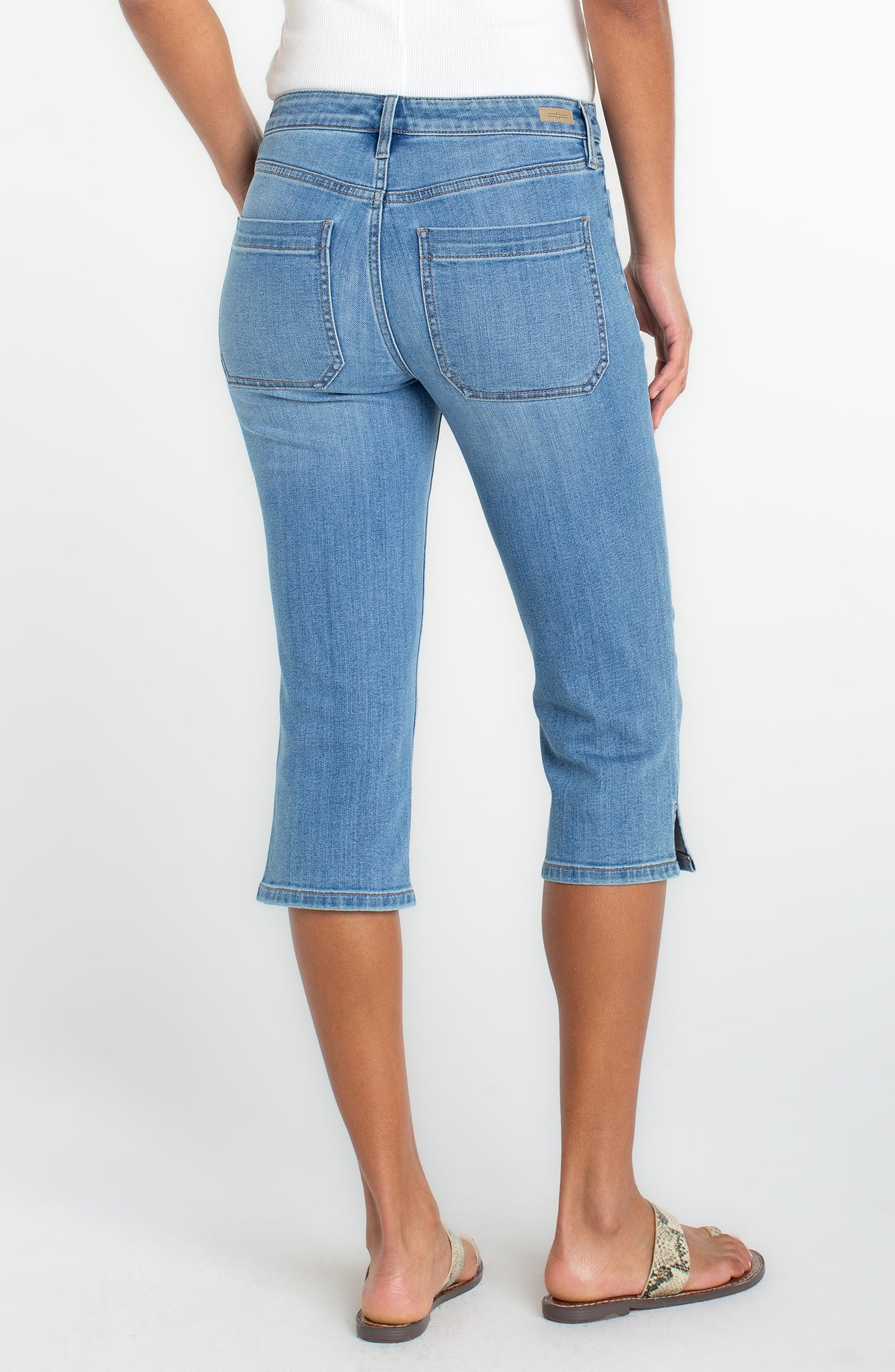 Back view of a woman wearing Liverpool Ocean Breeze Capri with Patch Pockets 19" Inseam in light blue denim.