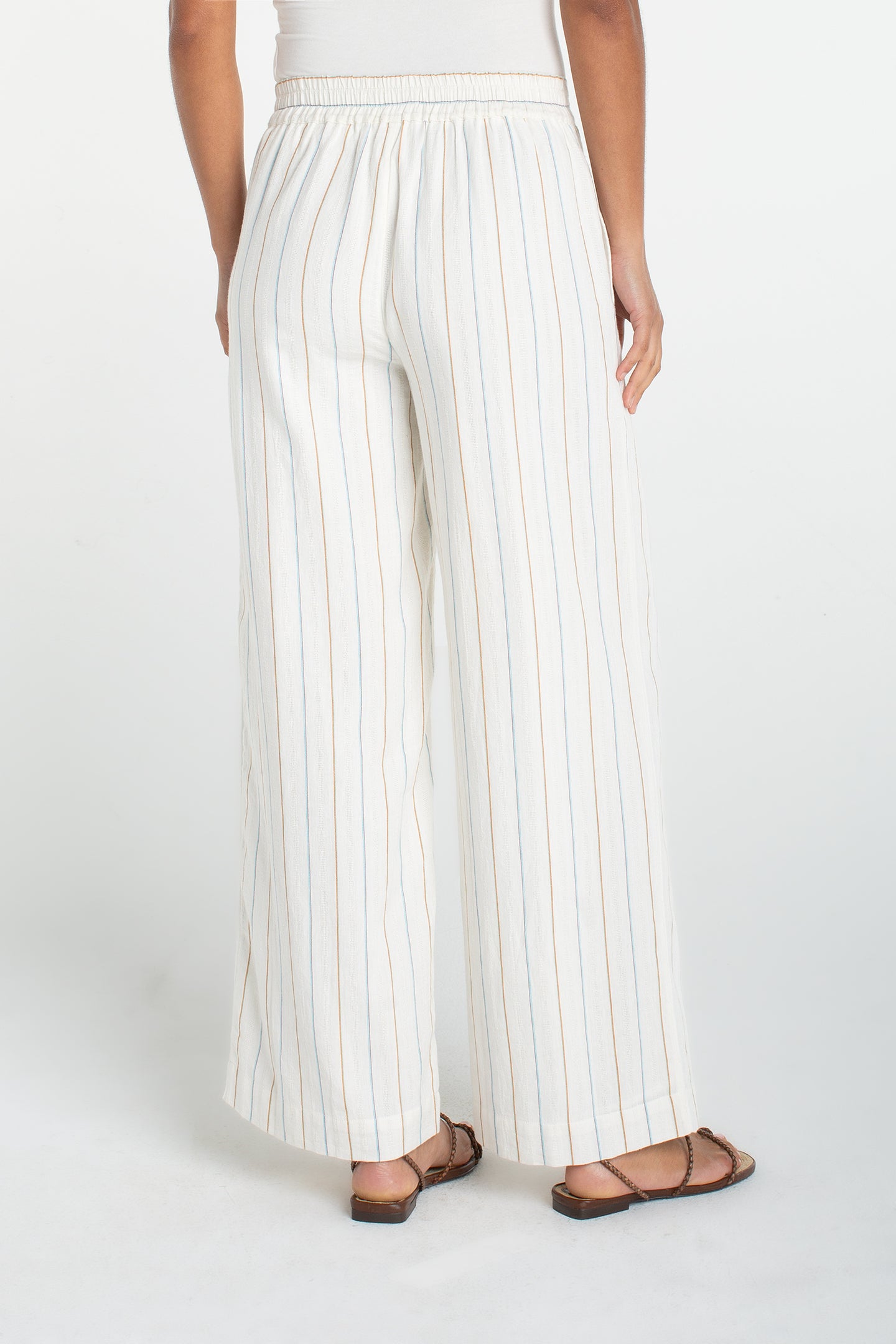 Back view of a model wearing Cream/Blue Multi Stripe Pull On Wide Leg Woven Pant by liverpool with sandals on a white background