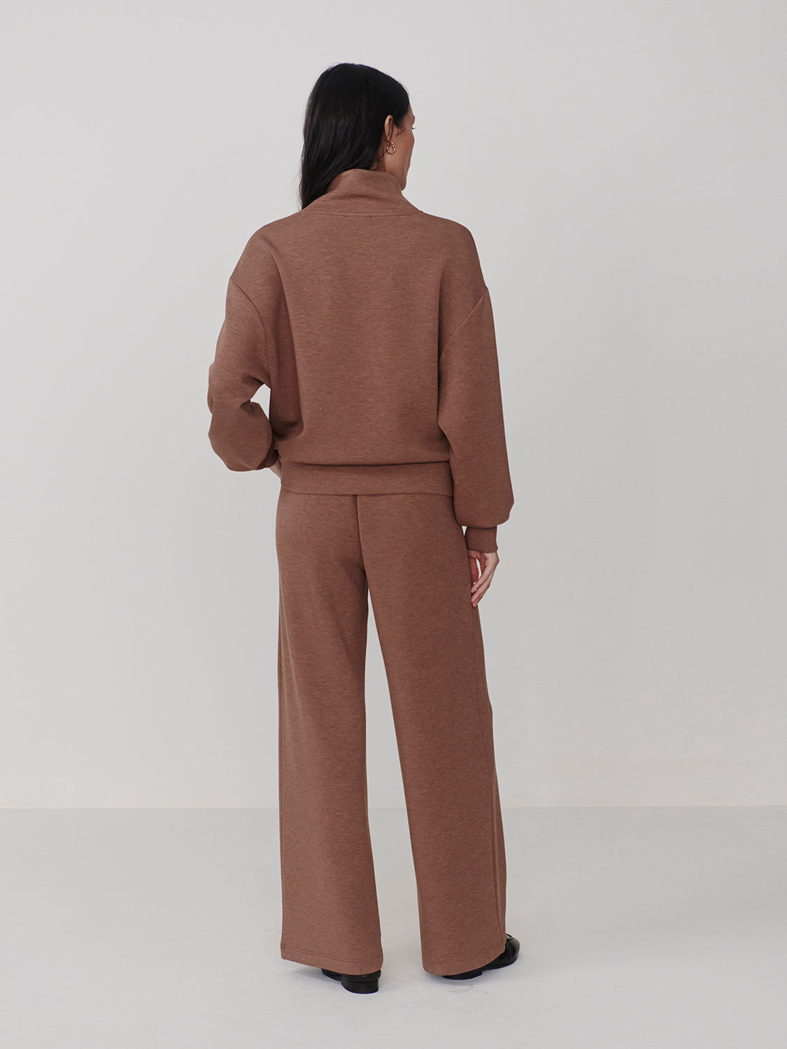 Woman wearing Varley Golden Bronze Marl The Extra Wide Leg Pant -29.5 in brown from the back, paired with a matching top.