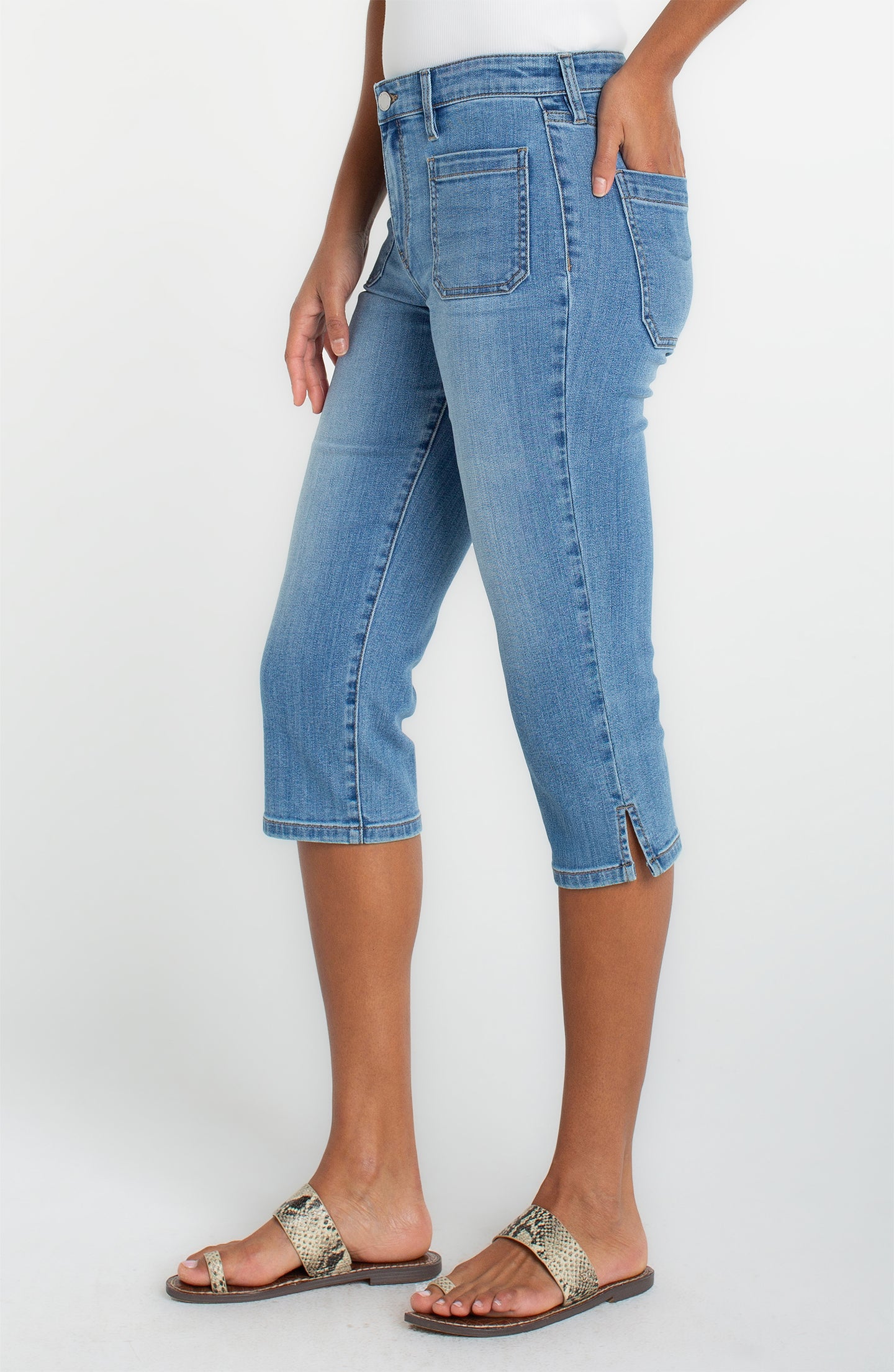 Woman wearing light blue denim Ocean Breeze Capri with Patch Pockets 19" Inseam by liverpool standing in sandals