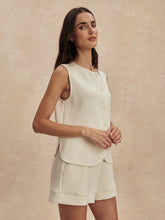 Woman wearing a sleeveless cream Prinstine Josie Button Through Tank by Varley paired with matching shorts against neutral background