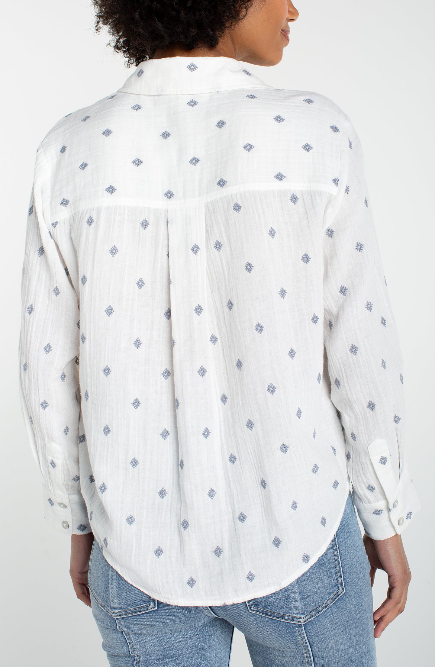 Back view of a woman wearing an Off White Long Sleeve Button Front Shirt With High Low Hem by liverpool with subtle diamond pattern.