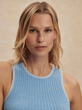 Close-up of a woman wearing a Mist Blue Hanson Rib Knit Tank by Varley with soft waves, neutral makeup, and a beige background.
