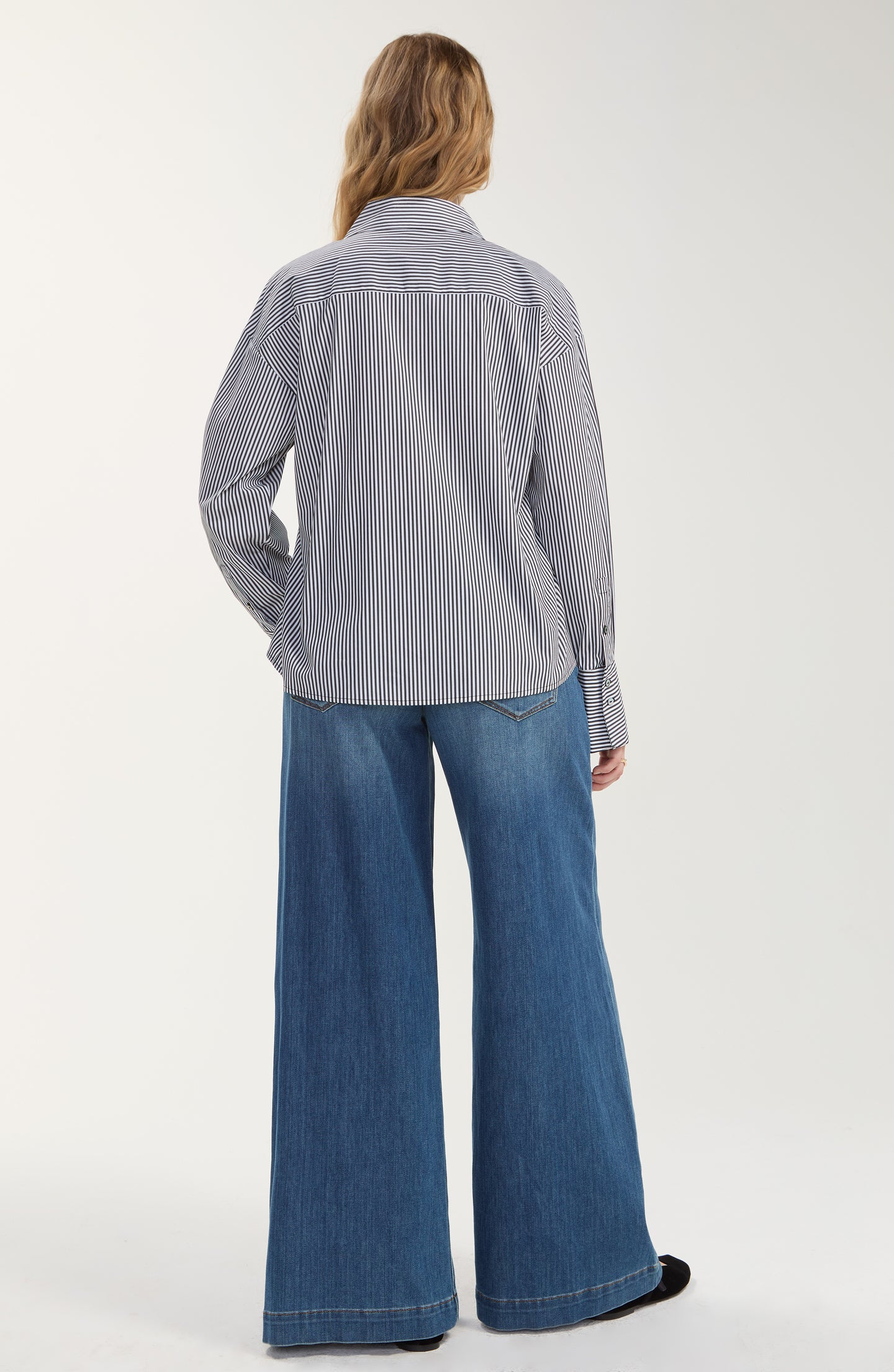 Back view of a person wearing a Black/White Stripe Long Sleeve Shirt with Embellishment by liverpool and wide-leg jeans