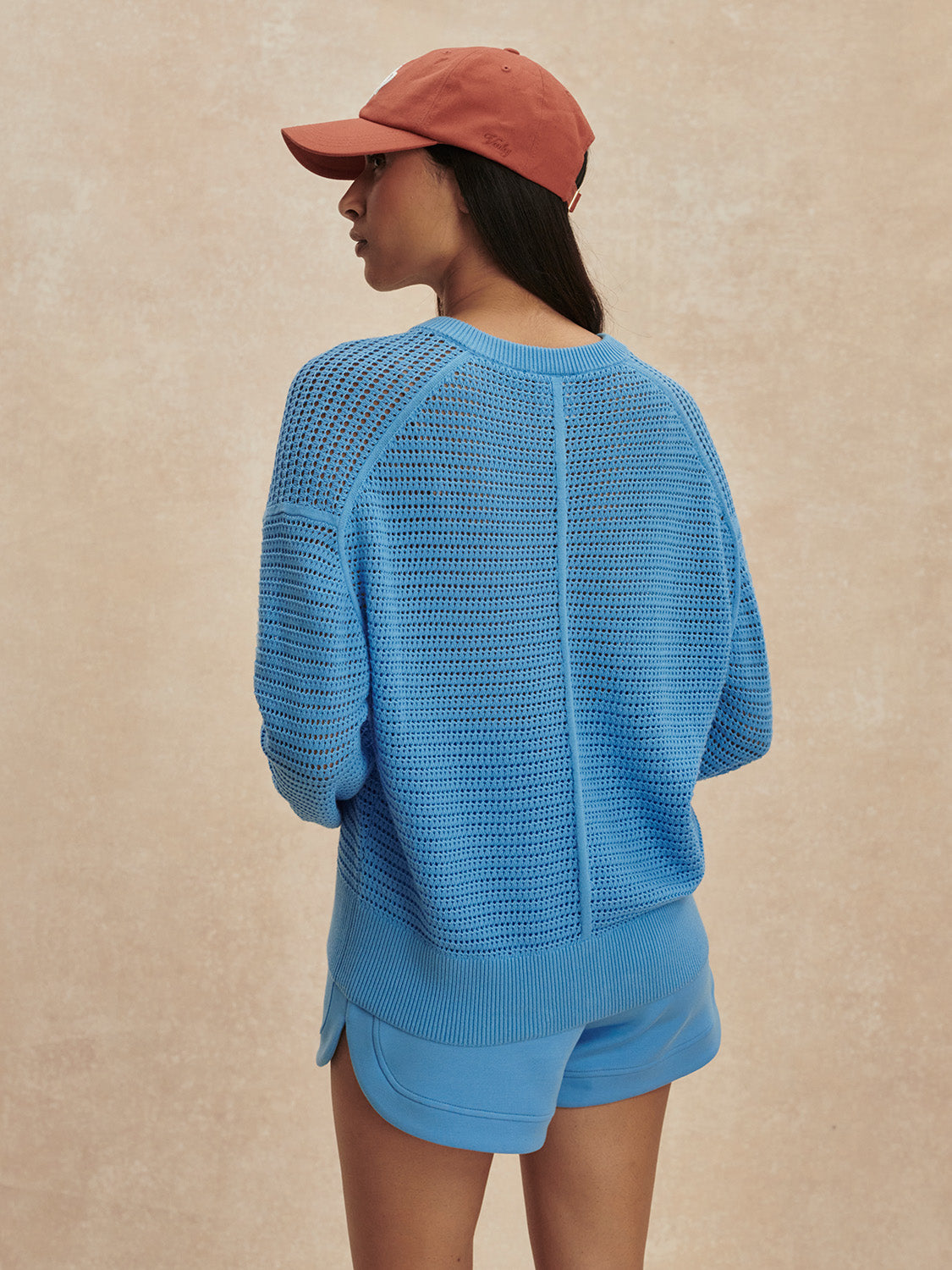Woman wearing an Azure Blue Pembroke Knit Cardigan by Varley, shown from back with relaxed fit and textured knit pattern.