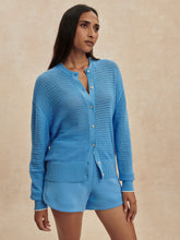 Woman wearing an Azure Blue Pembroke Knit Cardigan by Varley with matching shorts against neutral background