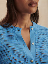 Close-up of a woman wearing an Azure Blue Pembroke Knit Cardigan by Varley with pearl buttons and textured knit pattern