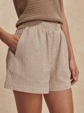 Close-up of a woman wearing Varley Birch Taupe Stripe Darina Short 4 with side pockets and a knit top