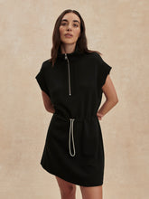 Woman wearing a sleek Black Avaya Half Zip Dress by Varley with a drawstring waist and short sleeves.