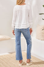 Back view of woman wearing Tribal Ocean Pearl Crinkle Gauze Top in white paired with embroidered blue jeans and platform shoes