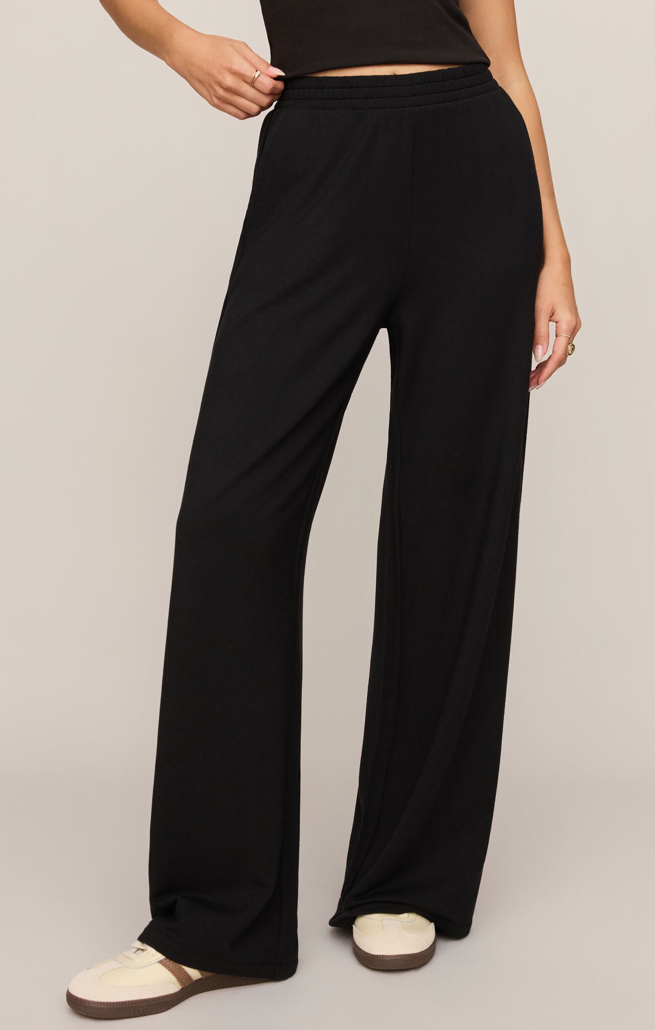 Model wearing black wide-leg Black In Transit Modal Pant by z supply with a cropped black top and white sneakers.