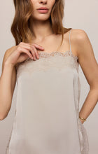 Woman wearing a cream camisole with lace trim and thin straps
