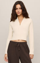 Woman wearing a cream ribbed Sandstone Summit Half Zip Sweater by z supply with dark brown drawstring pants.